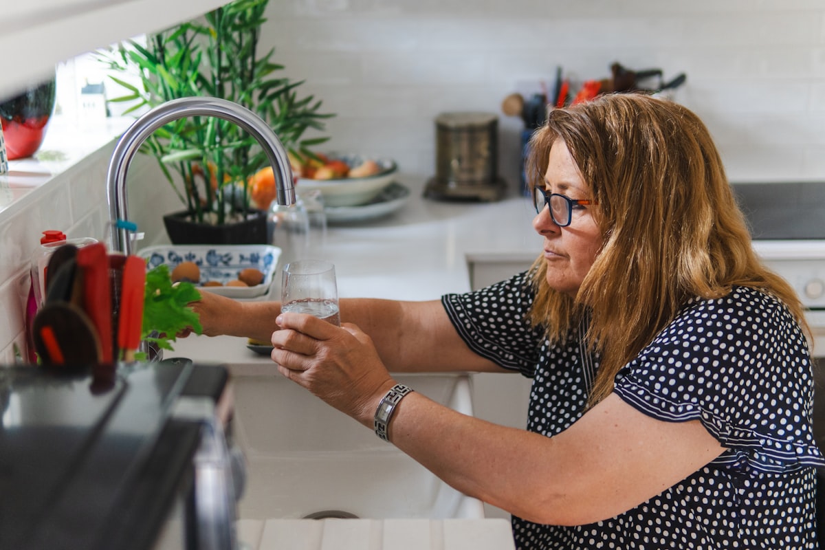 Ett glas rent vatten med citronskivor och is på en trädgårdsbord